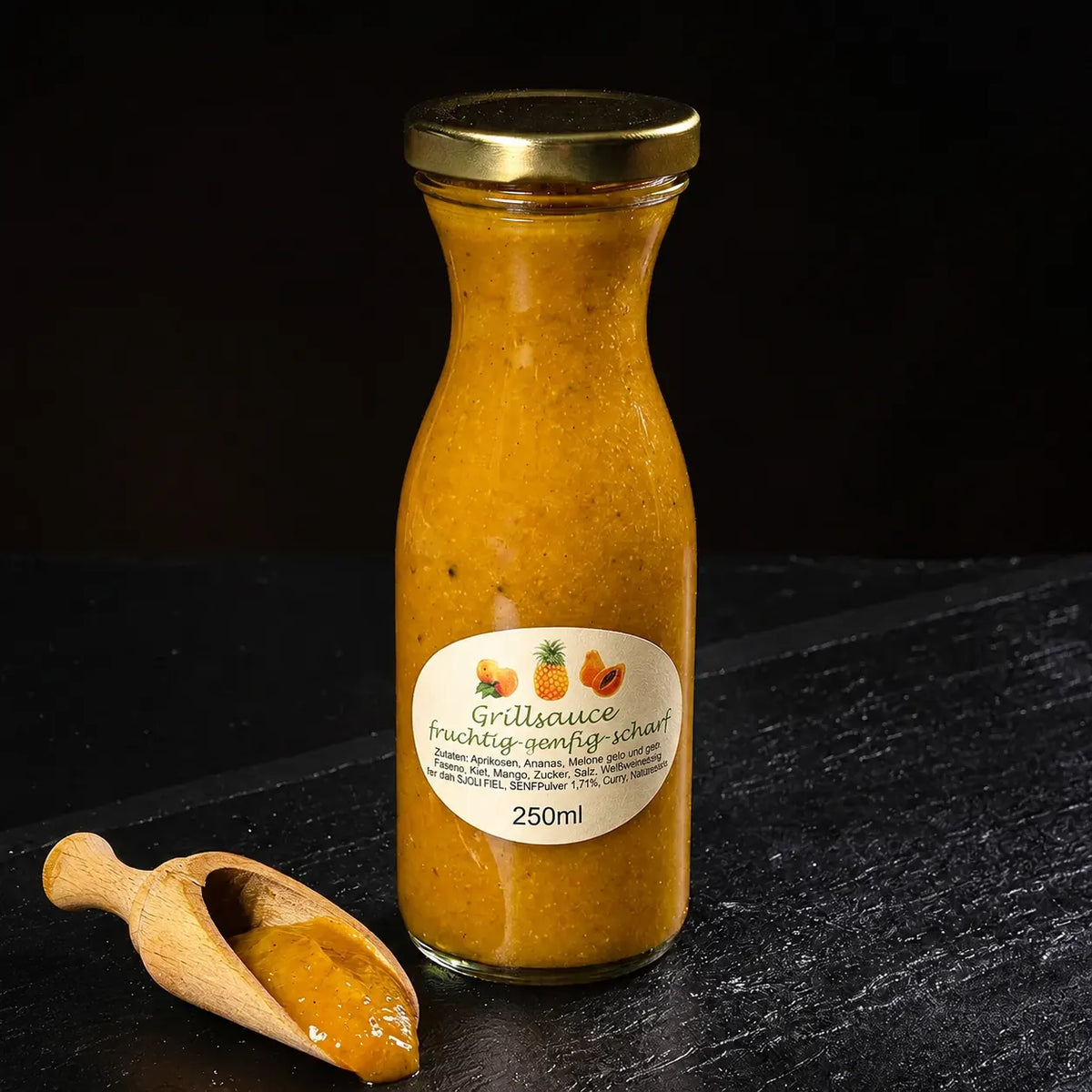 Gelbe Grillsauce in kleiner Glasflasche neben kleinem Holzlöffel vor dunklem Hintergrund.
