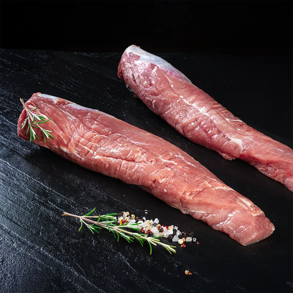 Zwei Schweinefilets vom Duroc Strohschwein von der Seite vor dunklem Hintergrund.